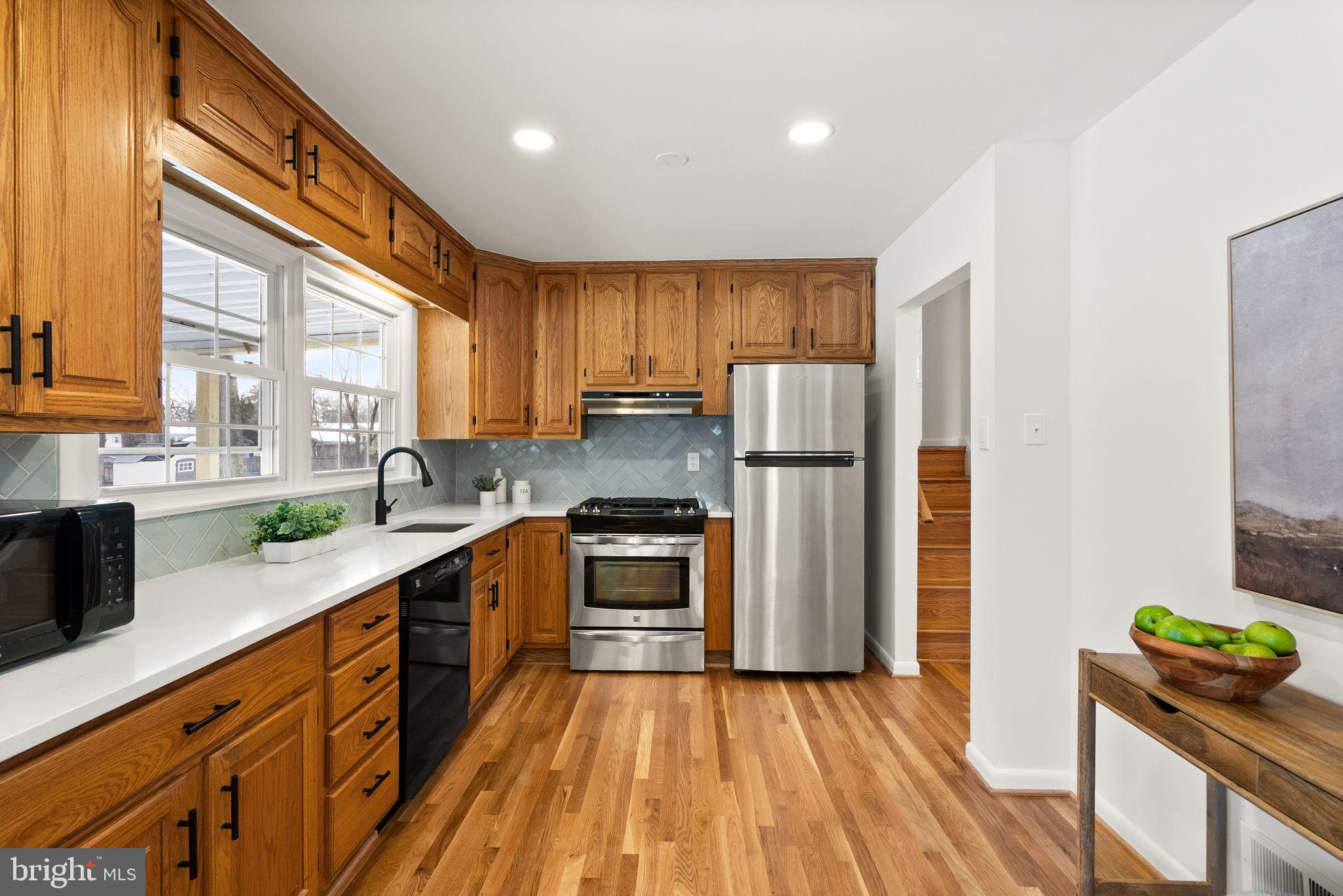 4217 Alcott Street Alexandria, VA 22309 - Photo 13 of 42 a kitchen with stainless steel appliances granite countertop a refrigerator a sink dishwasher a stove and white countertops with wooden floor