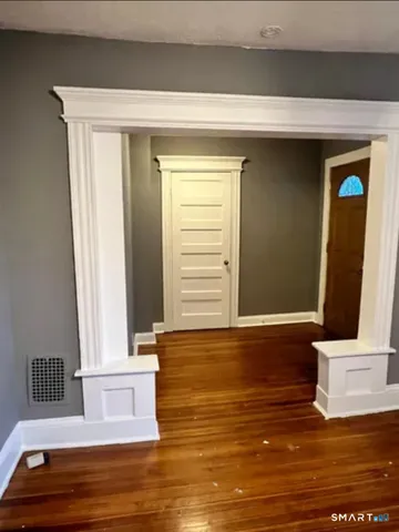 a view of an empty room with window and wooden floor