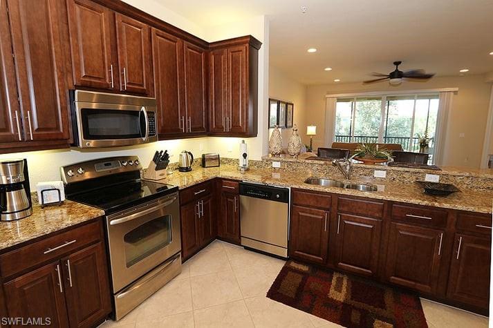 6525 Monterey Point, Unit 203 Naples, FL 34105 - Photo 6 of 25 Kitchen featuring stainless steel appliances, kitchen peninsula, light tile patterned floors, light stone countertops, and ceiling fan