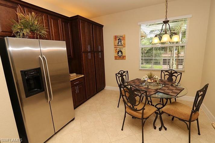 6525 Monterey Point, Unit 203 Naples, FL 34105 - Photo 7 of 25 Kitchen featuring stainless steel fridge with ice dispenser, a notable chandelier, light tile patterned floors, pendant lighting, and dark brown cabinetry