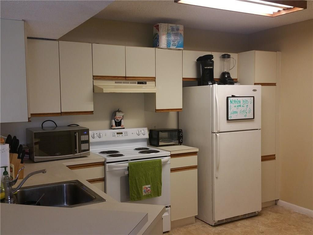 9001 Wiles Road, Unit 206 Coral Springs, FL 33067 - Photo 13 of 14 a kitchen with kitchen island a sink a stove and refrigerator