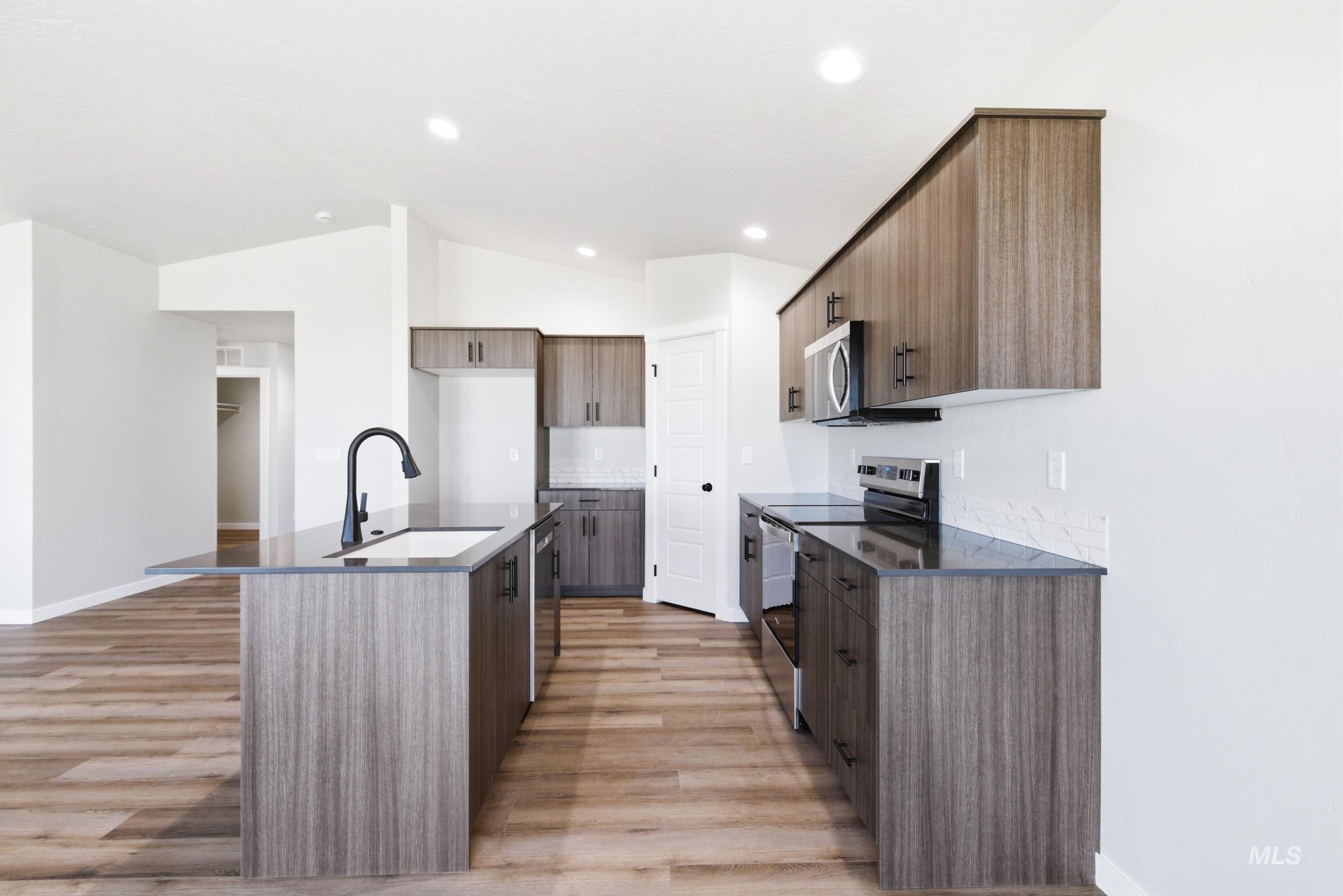12805 Decatur Street Nampa, ID 83651 - Photo 7 of 20 Modern kitchen featuring wood-finish cabinetry, black countertops, and stainless steel appliances
