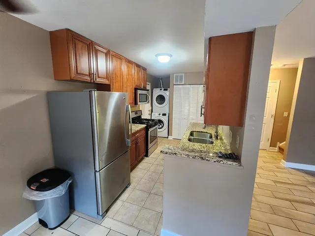 a kitchen with stainless steel appliances granite countertop a refrigerator a stove and a sink