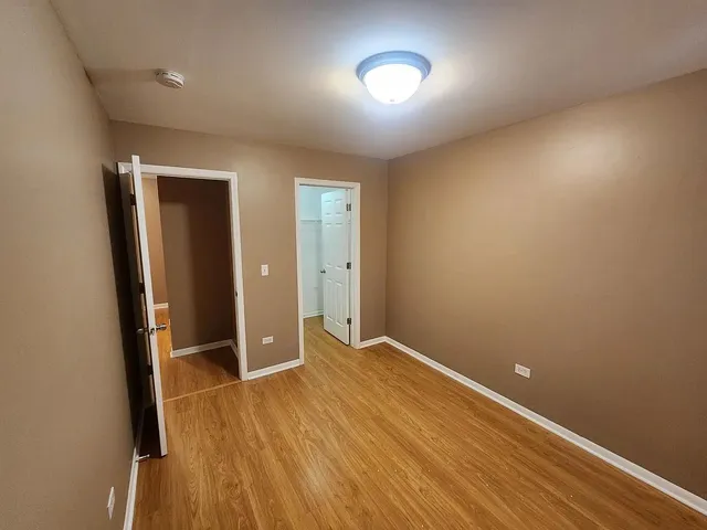 an empty room with wooden floor and mirror