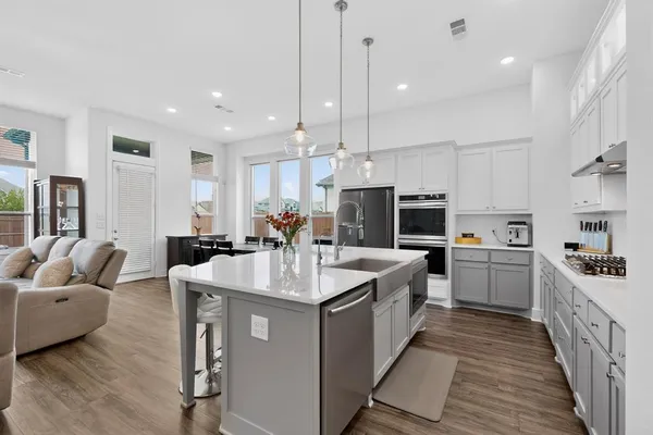 a large kitchen with kitchen island a large counter top space a sink stainless steel appliances and cabinets