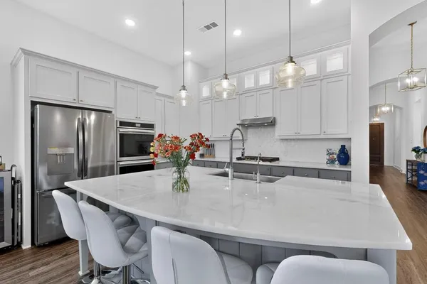 a kitchen with granite countertop a table chairs stainless steel appliances and wooden floor