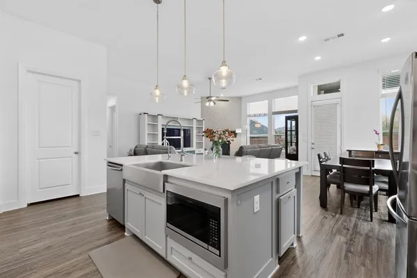 a large white kitchen with lots of counter space a sink appliances and dining table