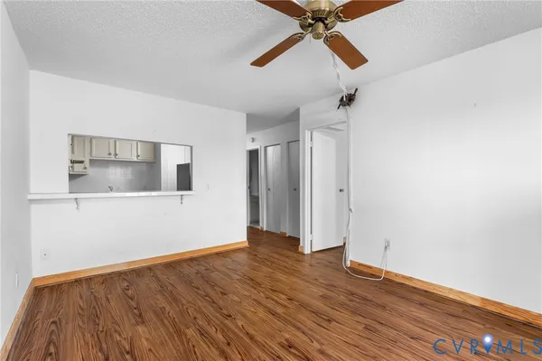 a view of an empty room with wooden floor and a ceiling fan