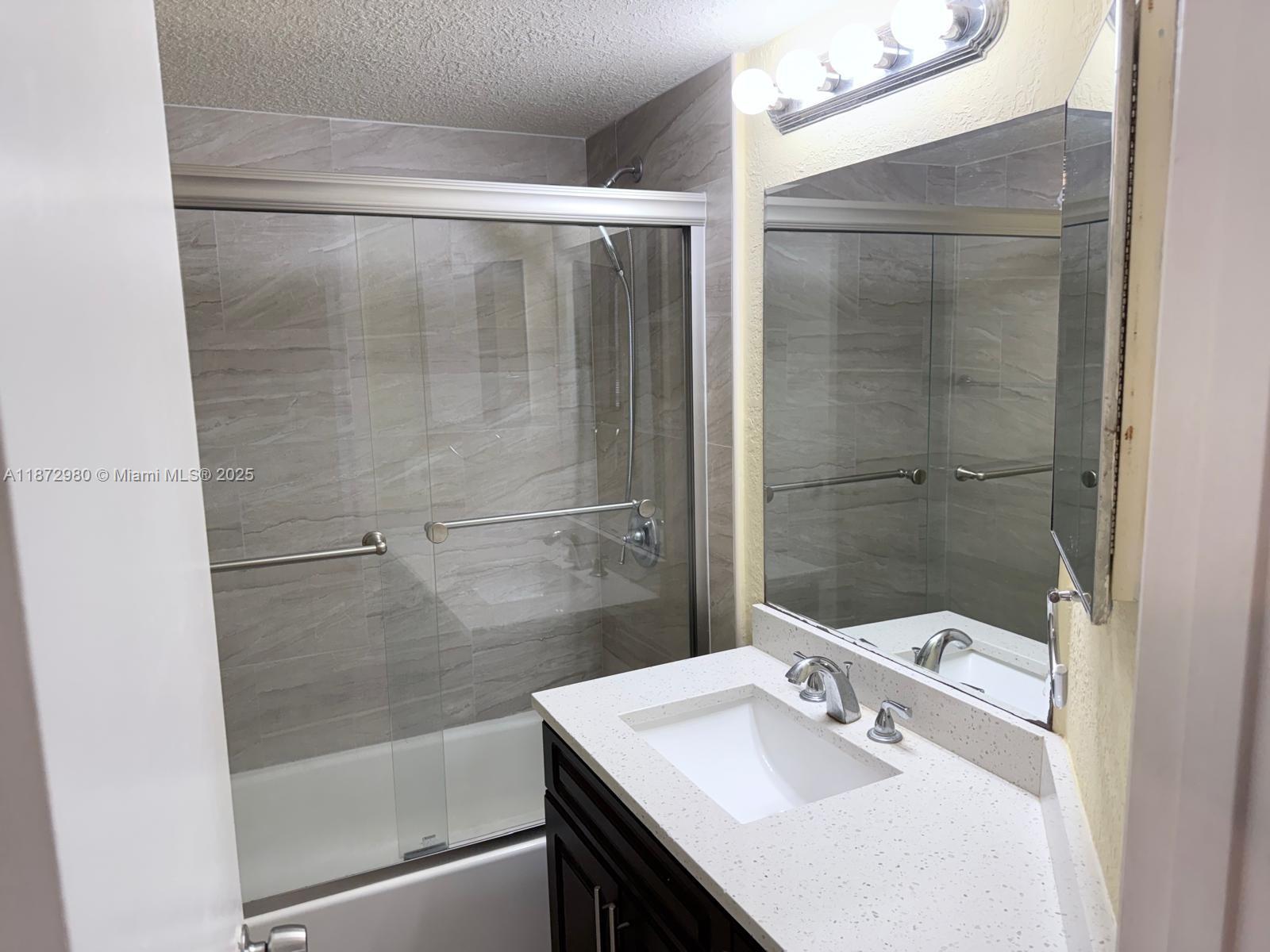 3224 Northwest 103rd Terrace, Unit 205B Coral Springs, FL 33065 - Photo 18 of 21 a bathroom with a sink mirror and shower