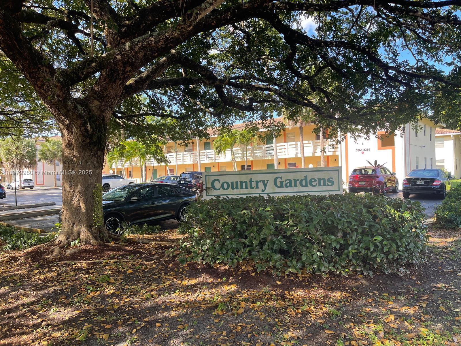3224 Northwest 103rd Terrace, Unit 205B Coral Springs, FL 33065 - Photo 2 of 21 a backyard of a house with table and chairs under a large tree