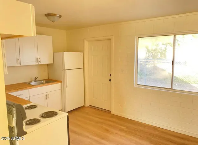 a kitchen with a refrigerator a stove cabinets and wooden floor