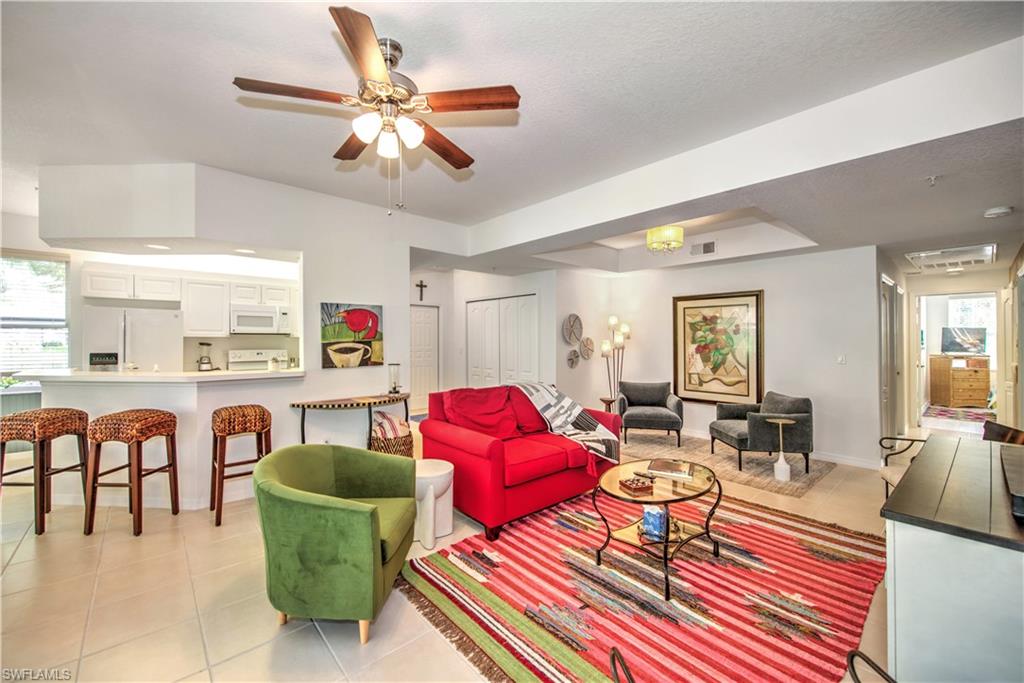 343 Dover Place, Unit A104 Naples, FL 34104 - Photo 13 of 36 a living room with furniture and a dining table with kitchen appliances