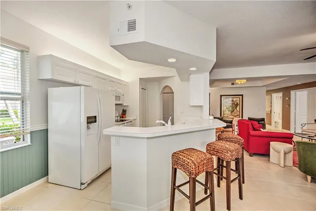a living room with furniture and a refrigerator
