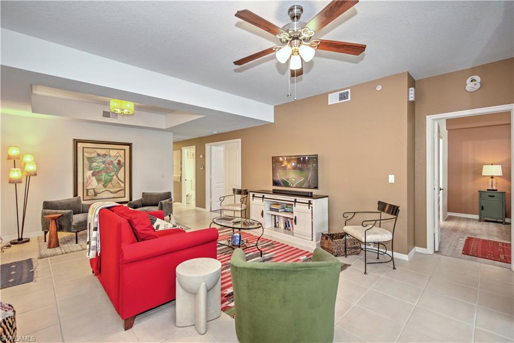 343 Dover Place, Unit A104 Naples, FL 34104 - Photo 20 of 36 a living room with furniture a chandelier and a flat screen tv