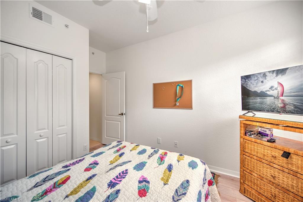 343 Dover Place, Unit A104 Naples, FL 34104 - Photo 28 of 36 a bedroom with a bed and a cabinet