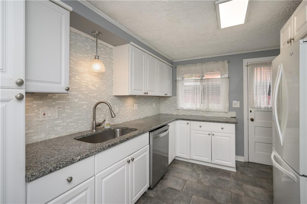 501 Sangree Road Pittsburgh, PA 15237 - Photo 8 of 29 a kitchen with granite countertop a sink stainless steel appliances white cabinets and a window
