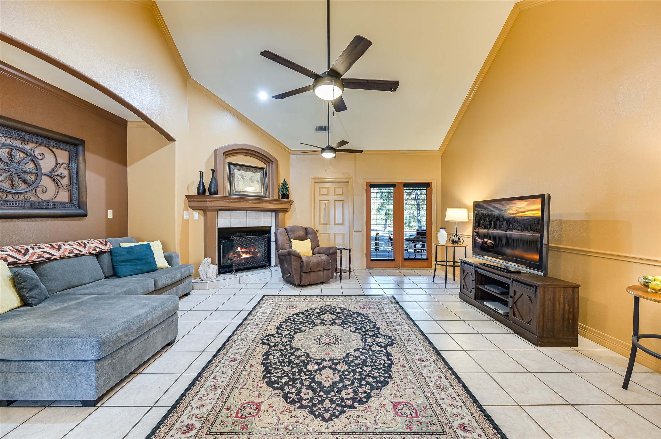 486 Westwood Road Lockhart, TX 78644 - Photo 6 of 29 Living area featuring crown molding, high vaulted ceiling, light tile floors, a tiled fireplace, and a ceiling fan