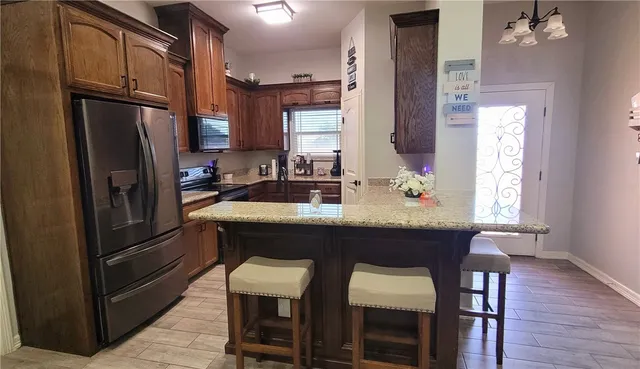 a kitchen with stainless steel appliances granite countertop a dining table chairs refrigerator and sink