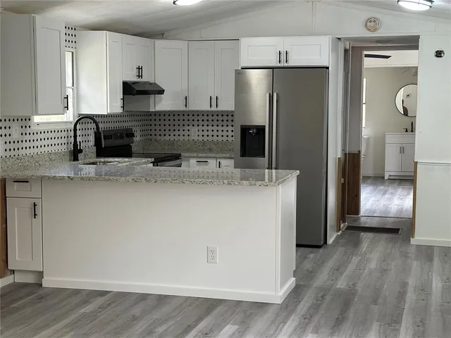 a view of a kitchen with a sink refrigerator and wooden floor