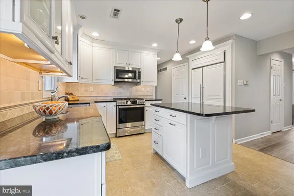 a kitchen with stainless steel appliances granite countertop a sink a stove and a refrigerator