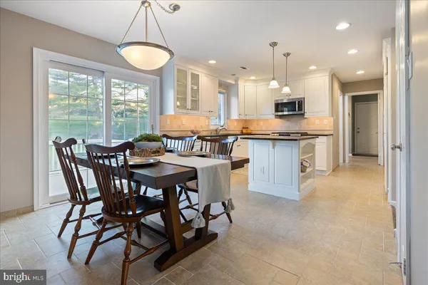 a dining area with a table chairs and a kitchen view