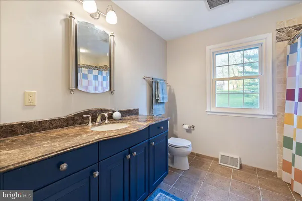 a bathroom with a granite countertop toilet sink and mirror