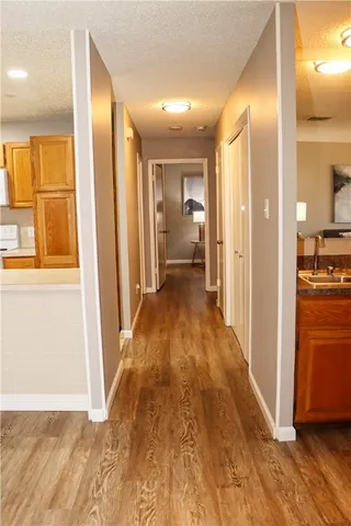 a view of a hallway with wooden floor and a bathroom