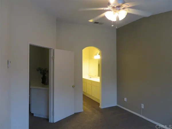 an empty room with a bathroom and a chandelier fan
