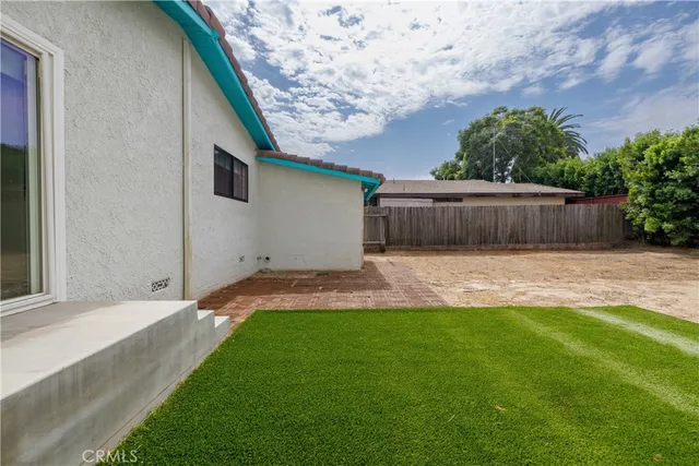 a view of a house with a yard potted plants and a bench