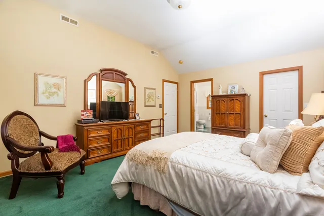 a bedroom with a bed a dresser and chair