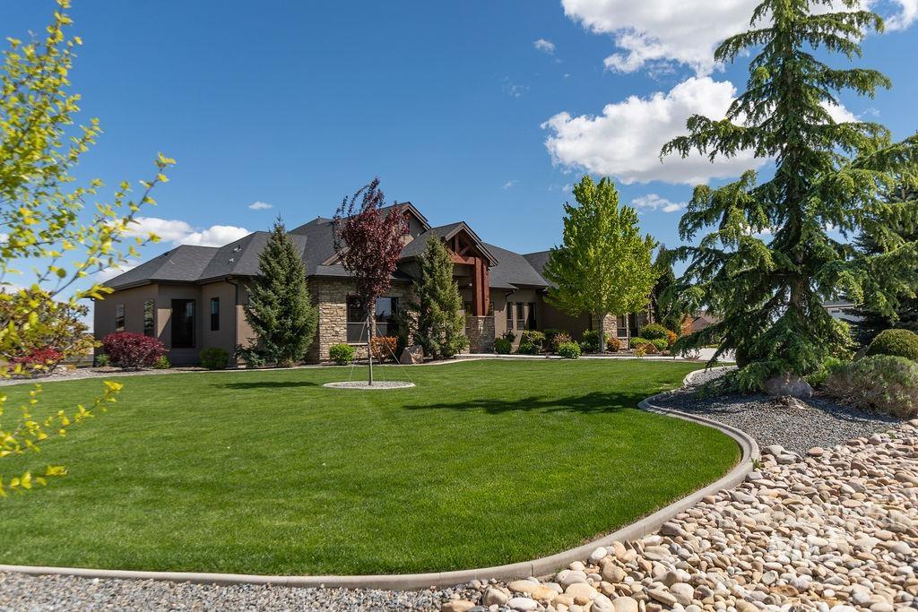 Sprawling front lawn with mature trees and stone landscaping
