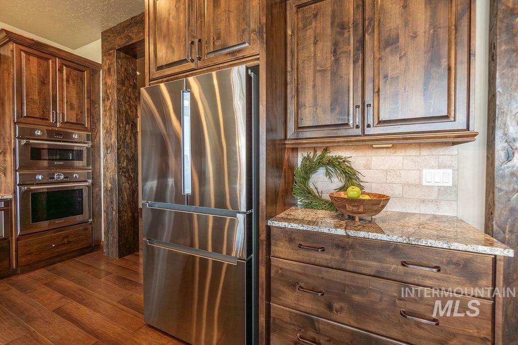 15350 Syrah Court Caldwell, ID 83607 - Photo 14 of 50 Kitchen featuring rich wood cabinetry, stainless steel appliances, a built-in double oven, and granite countertops