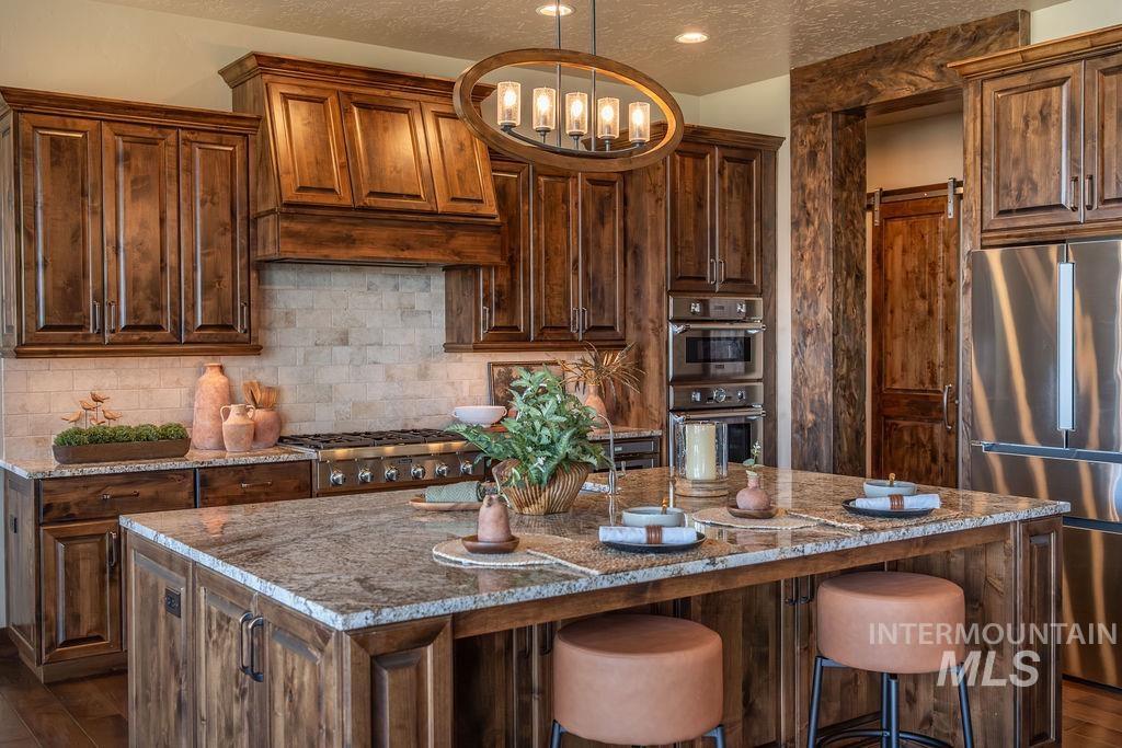 15350 Syrah Court Caldwell, ID 83607 - Photo 19 of 50 Kitchen featuring extensive wood cabinetry, a central island with a stone countertop, and stainless steel appliances
