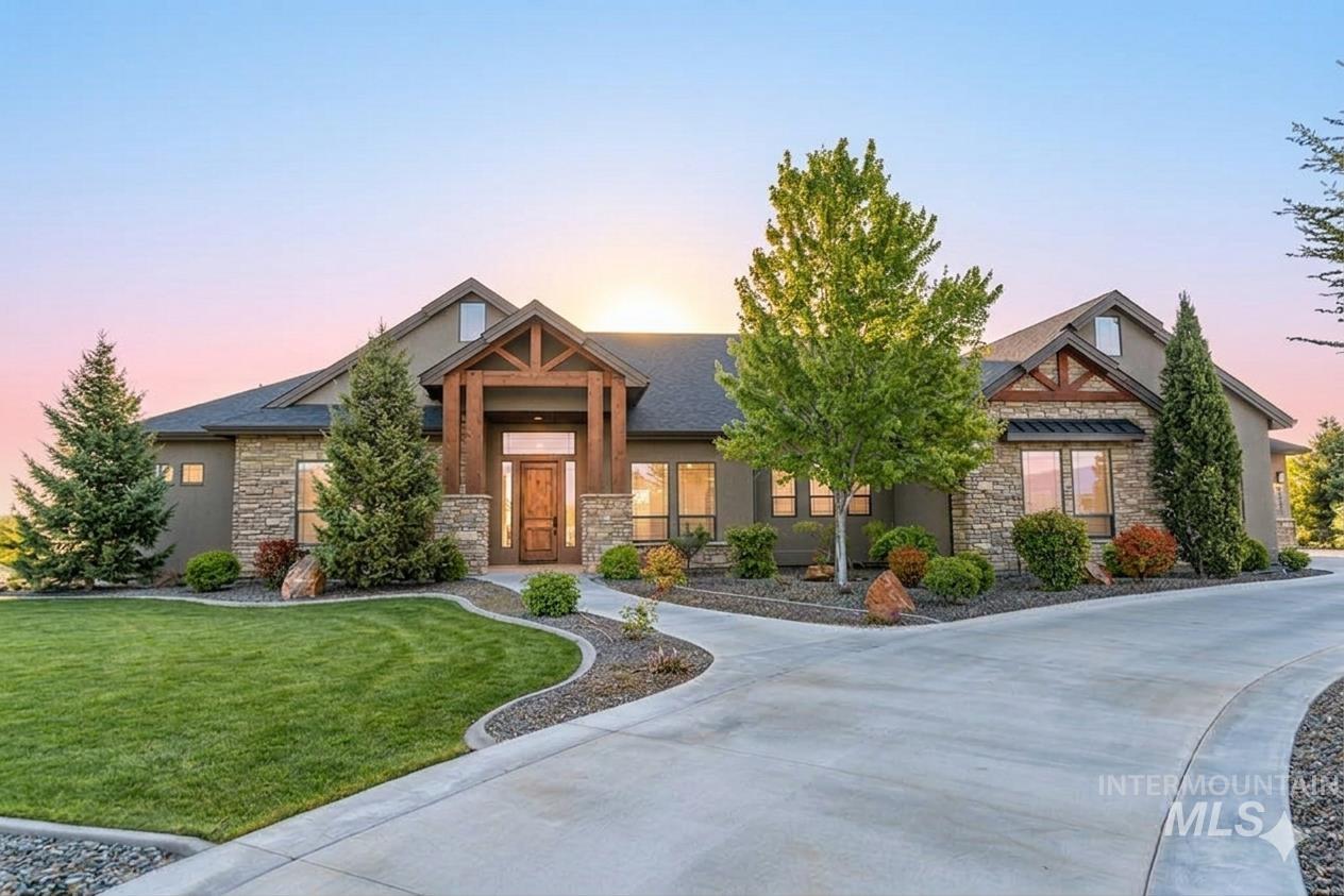 15350 Syrah Court Caldwell, ID 83607 - Photo 2 of 50 Craftsman-style exterior with stone veneer accents, a prominent timber-framed entry, dark roof, and a concrete driveway