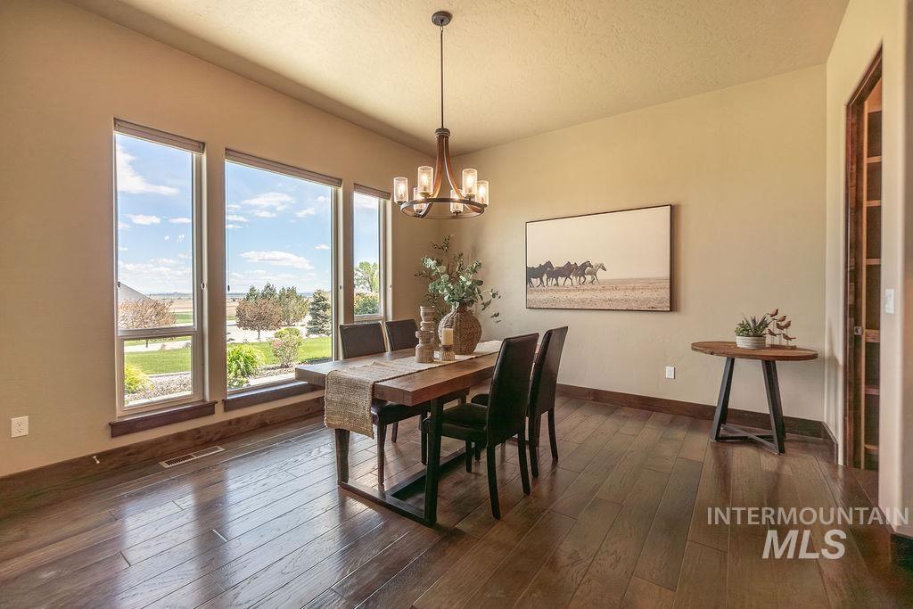 15350 Syrah Court Caldwell, ID 83607 - Photo 22 of 50 Dining area featuring large picture windows, wood-finish flooring, a contemporary chandelier, recessed ceiling lighting, and a built-in shelving unit