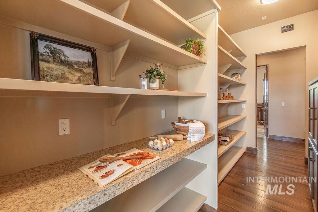 15350 Syrah Court Caldwell, ID 83607 - Photo 26 of 50 Spacious pantry featuring extensive light-colored shelving, a durable granite-finish countertop, and rich wood-finish flooring