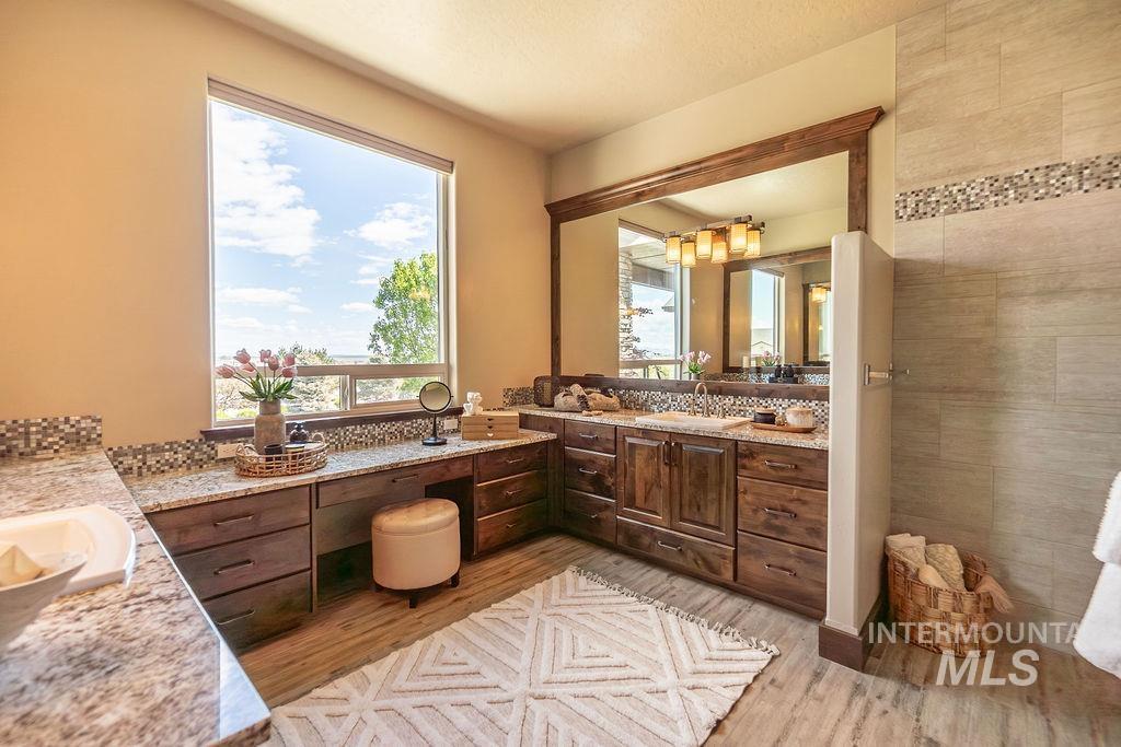 15350 Syrah Court Caldwell, ID 83607 - Photo 32 of 50 Spacious bathroom featuring a large window, dark wood-finish cabinetry, light granite countertops, and wood-finish flooring