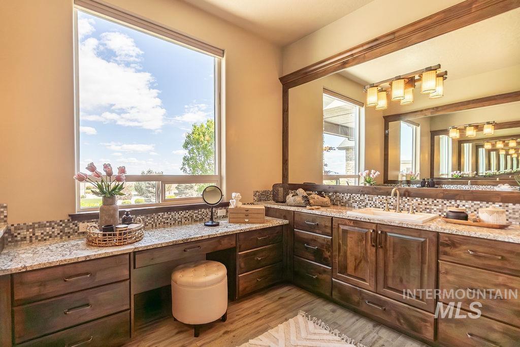 15350 Syrah Court Caldwell, ID 83607 - Photo 34 of 50 Spacious vanity area featuring rich wood cabinetry with extensive storage, granite-finish countertops, and a mosaic tile backsplash