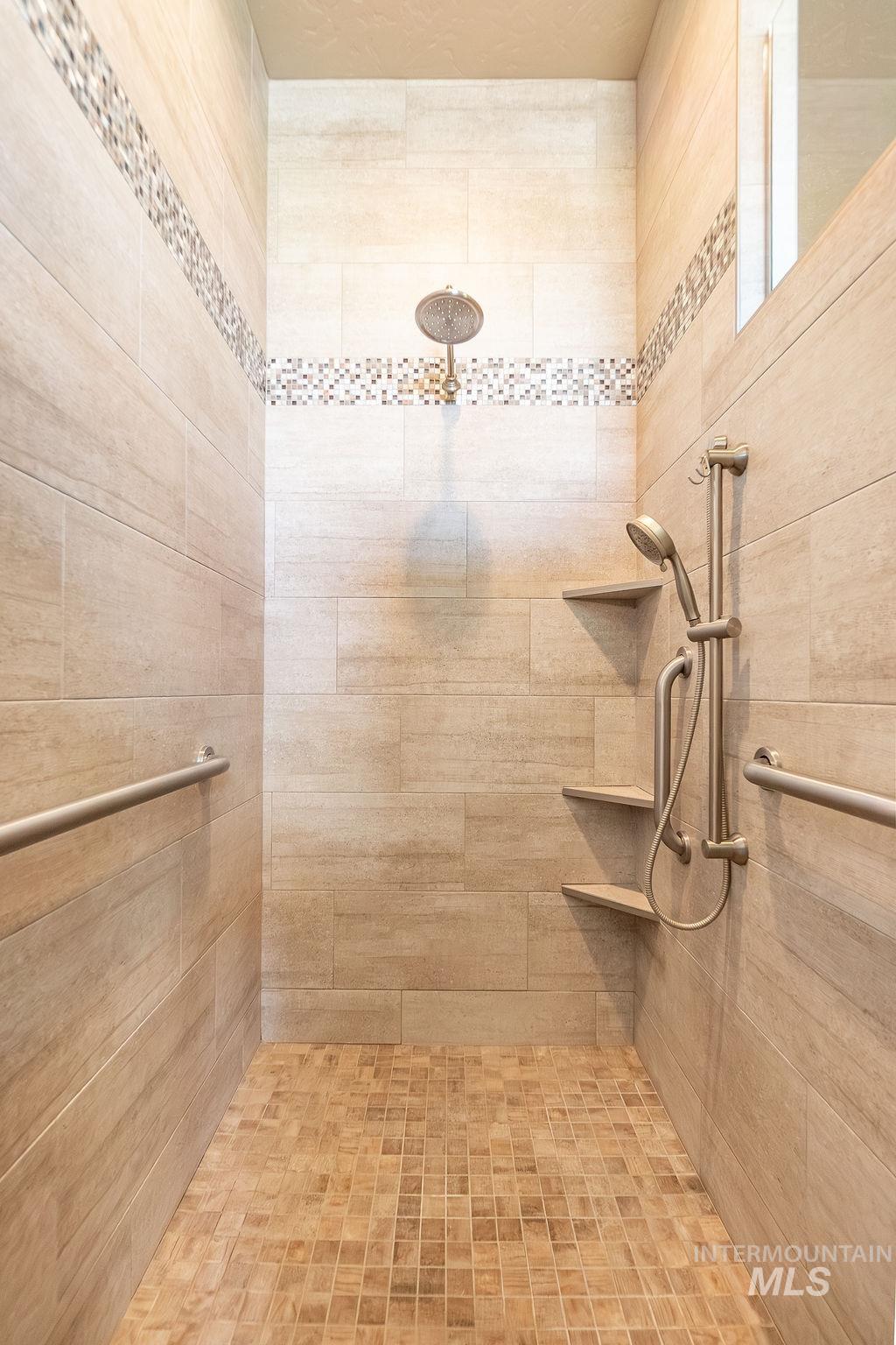 15350 Syrah Court Caldwell, ID 83607 - Photo 36 of 50 Spacious walk-in shower featuring large format wall tiles, a decorative mosaic tile accent band, and a mosaic tile floor