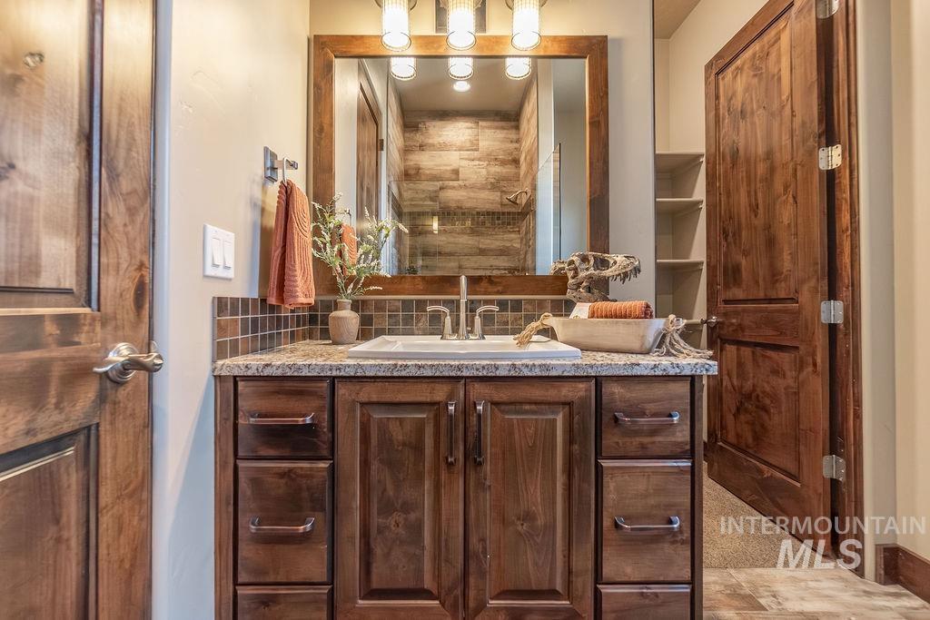 15350 Syrah Court Caldwell, ID 83607 - Photo 44 of 50 Wood-finish vanity with a stone countertop, integrated sink, and bronze faucet