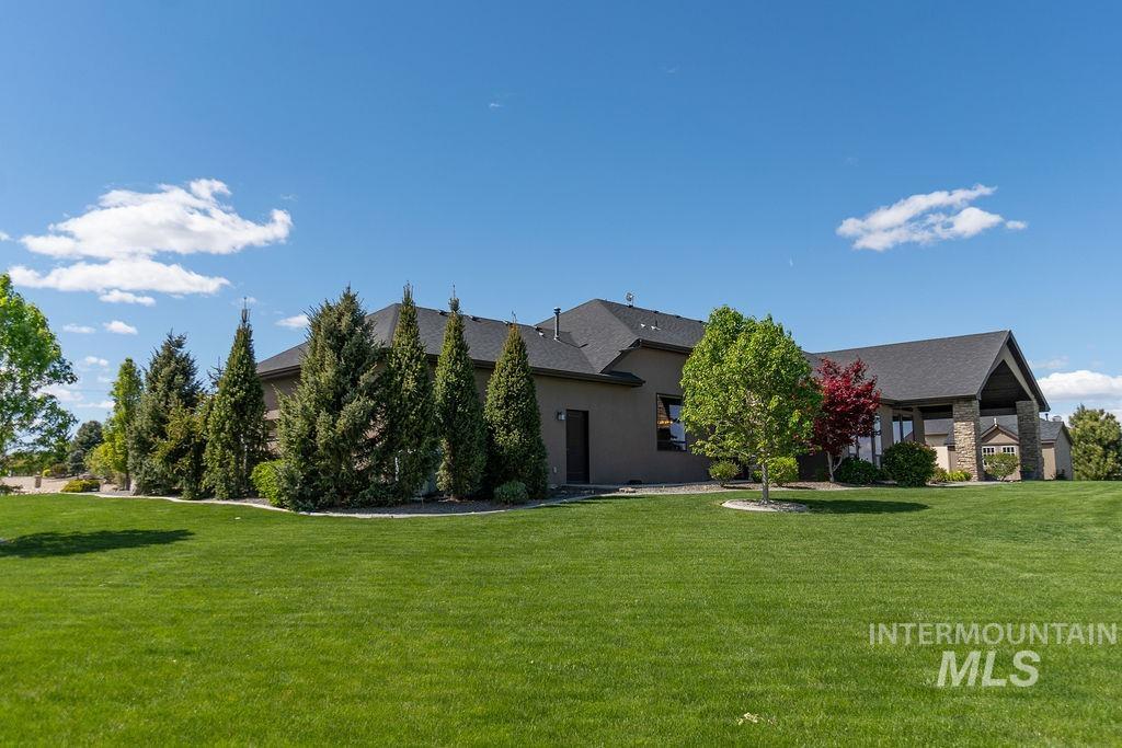 15350 Syrah Court Caldwell, ID 83607 - Photo 48 of 50 Expansive green lawn surrounds the property, featuring mature evergreen trees and diverse landscaping