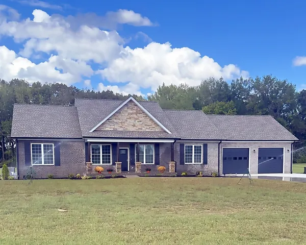 a view of a big house with a big yard and large trees