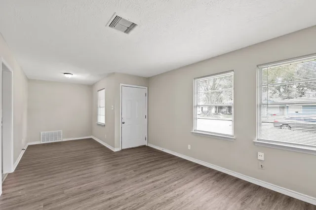 a view of an empty room with wooden floor and a window