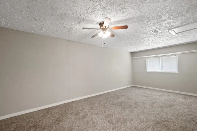 an empty room with a window and a ceiling fan