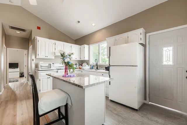 a kitchen with a white refrigerator a sink a stove a dining table and chairs