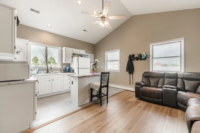 a living room with furniture a dining table wooden floor and a large window