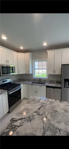 a kitchen with stainless steel appliances granite countertop a stove a sink and a microwave