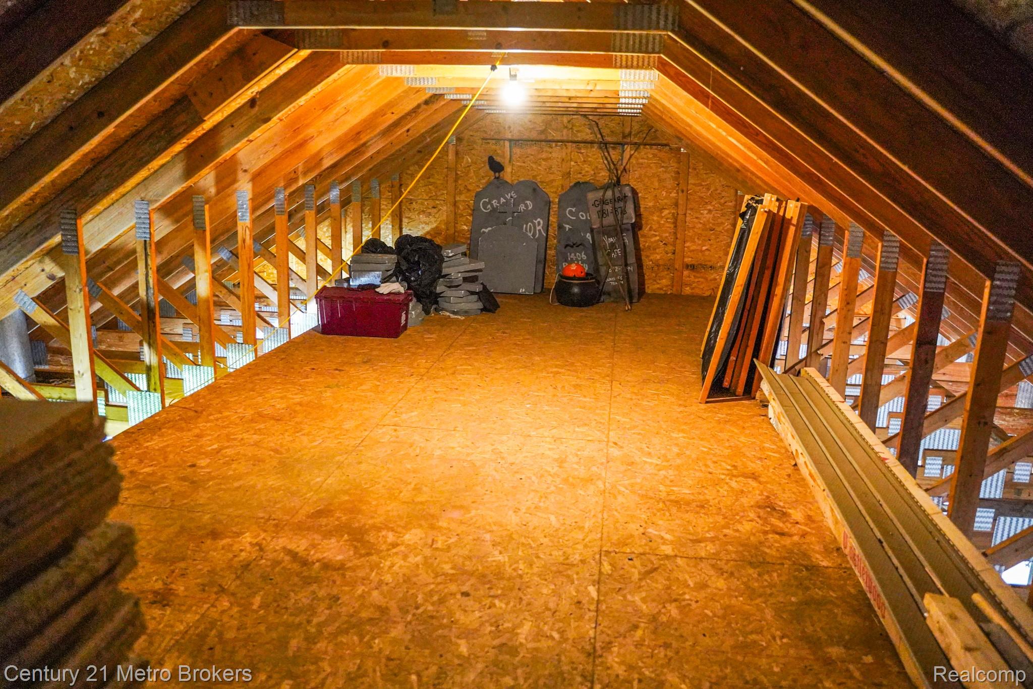 301 Field Road Clio, MI 48420 - Photo 32 of 32 Spacious unfinished attic space featuring exposed wood framing, plywood flooring, and an overhead light fixture