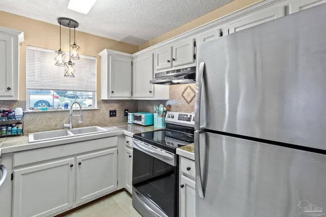 a kitchen with a sink a refrigerator and cabinets