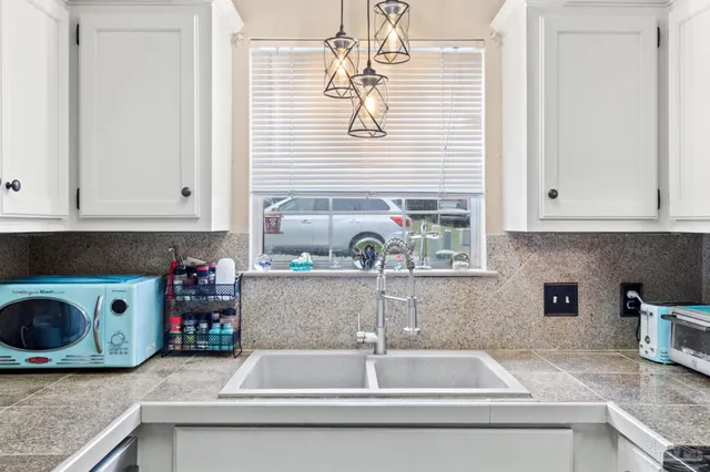 a kitchen with granite countertop a sink and a white wooden cabinets